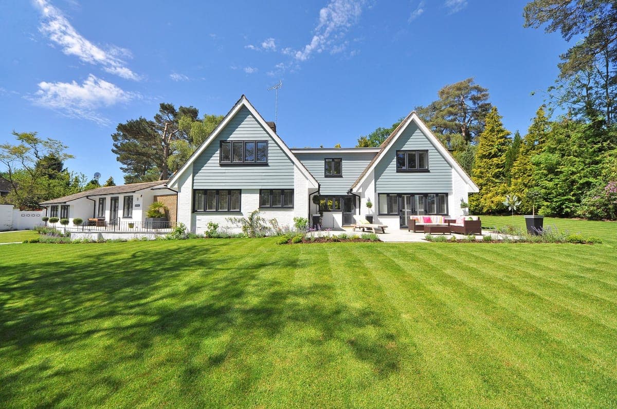 White lap-siding home with crisp gables on a wide green lawn under a clear sky