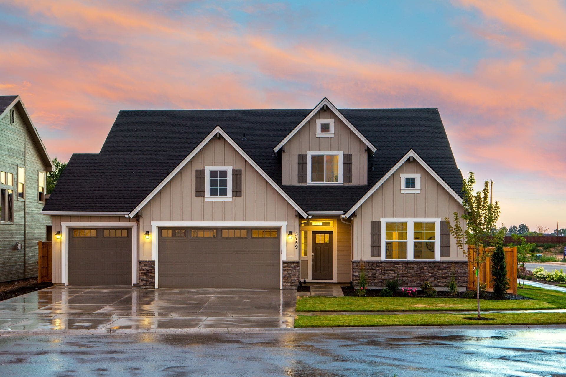 Suburban craftsman home under a clearing sunset sky, driveway still wet from the storm